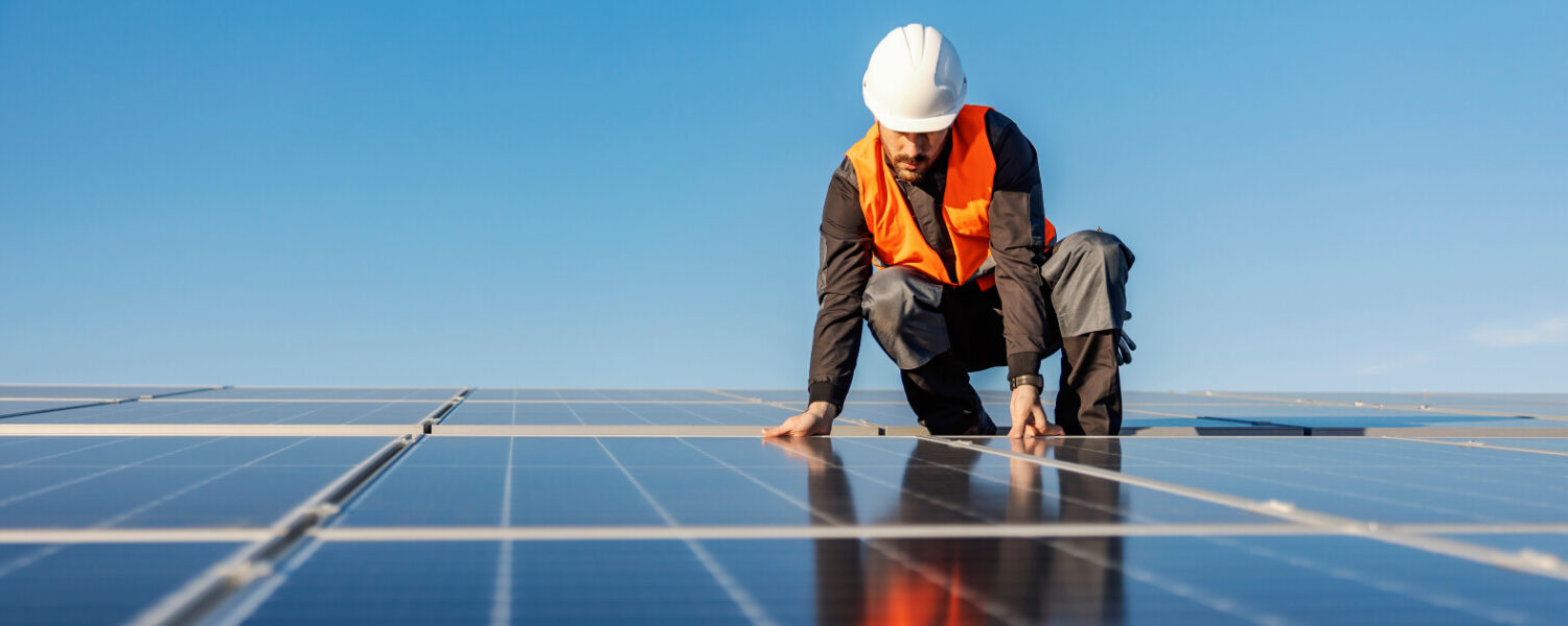 Person checking solar panels on roof